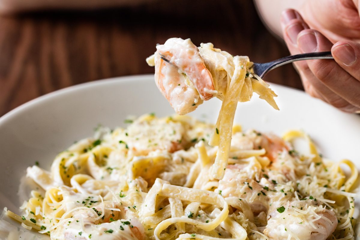 fork twirling noodles over a plate of shrimp linguine