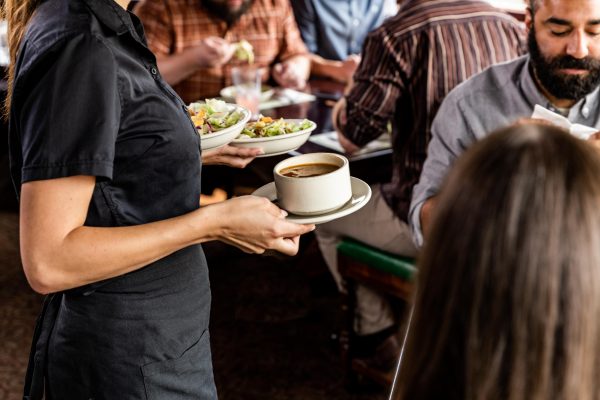 server carrying coffee and salads to table at The Old Spaghetti Factory