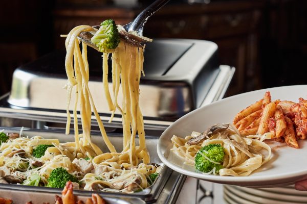 plate being filled at catering trays of pasta