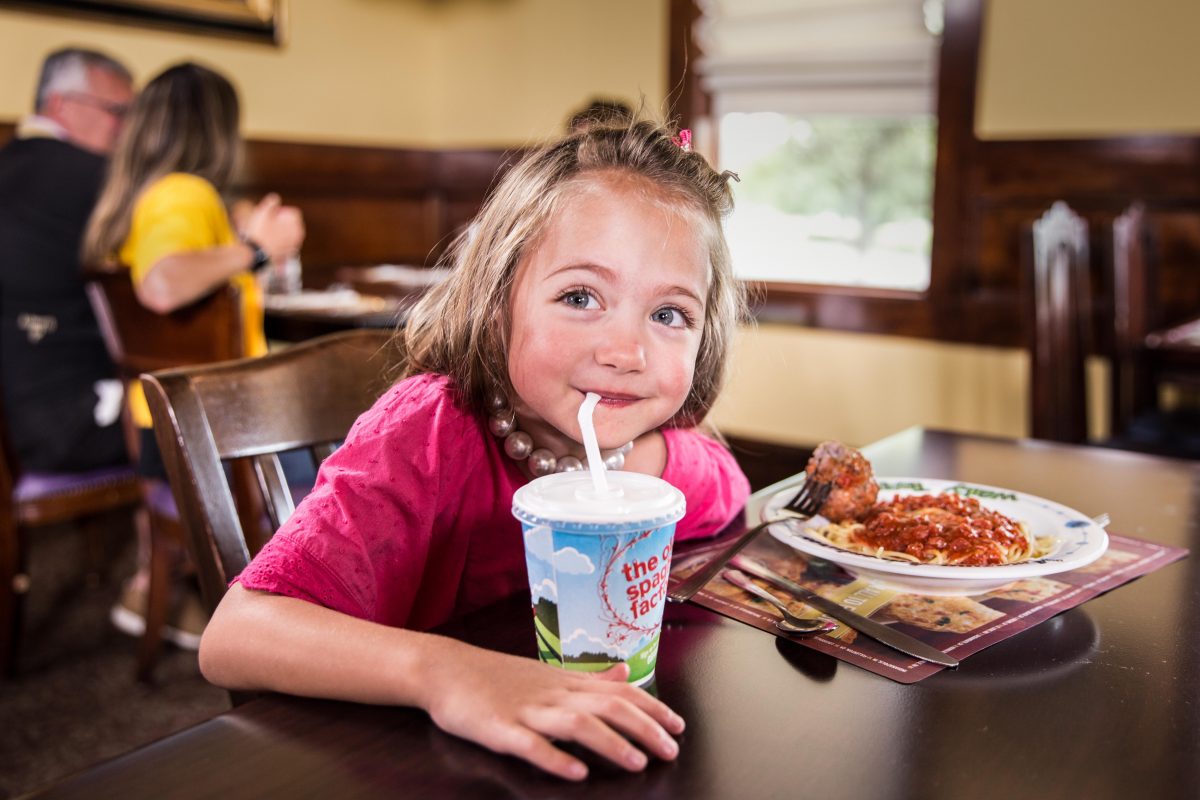 child drinking from a straw and eating pasta at The Old Spaghetti Factory